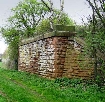 Built in Bulwell stone, a substantial bridge abutment looks west towards an embankment.