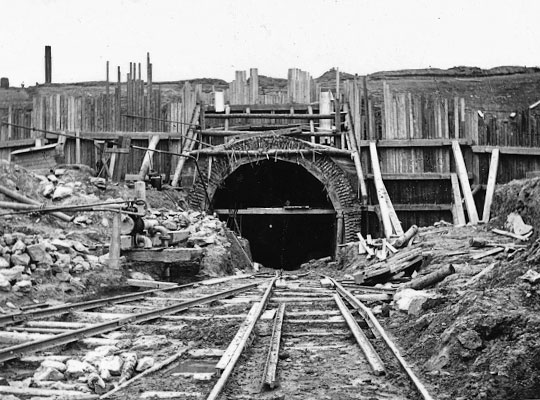 Although the excavation work is finished, timber piling holds the ground back above the tunnel entrance, in lieu of a portal.