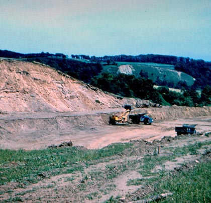 Looking north-east, a view of a Traxcavator loading lorries. The sandy nature of the soil is evident.