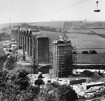 A remarkable shot taken during construction, showing the aerial ropeway (Blondin) used to carry materials across the valley.