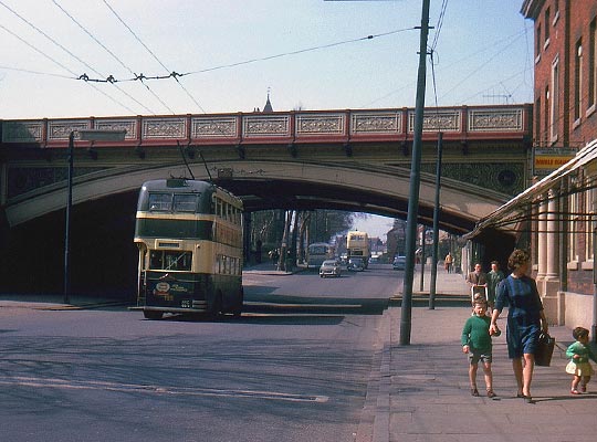 A trolleybus passes under the bridge on 18th April 1964.