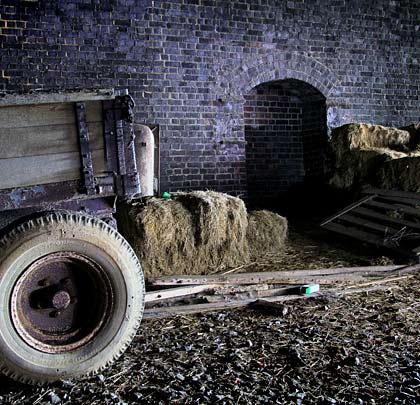 A collection of old agricultural machinery is stored inside the tunnel.