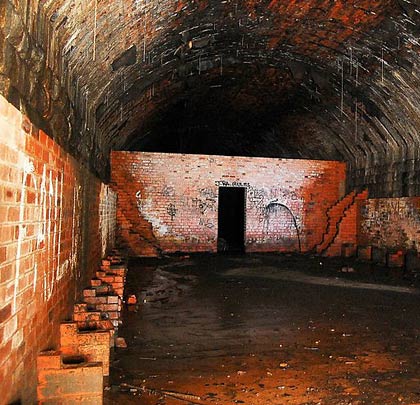 Inside is a wartime air raid shelter, with concrete floor and brick supports for benches.