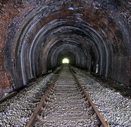 A single track remains in situ along the tunnel's centreline, raised on a substantial ballast formation.