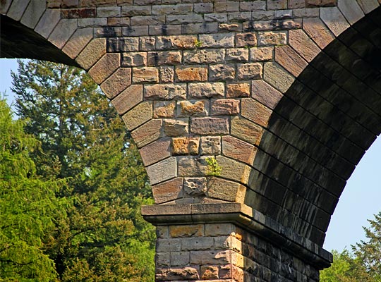 Whilst the spandrels are constructed from rusticated stone laid in courses, the arches themselves are ashlar.