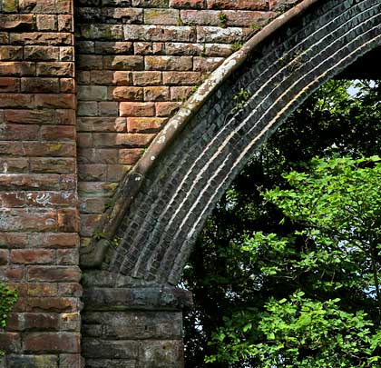 Edged by a rounded string course, the skew arch spans the River Gegin and comprises seven rings of engineering brick.