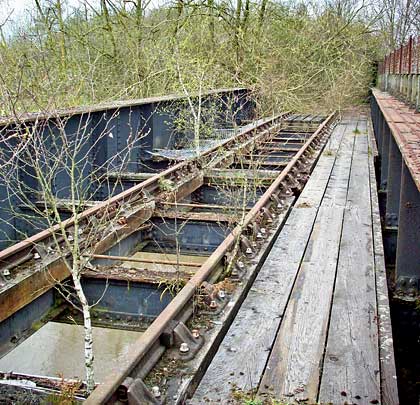 The timber waybeams still support their rails but sections of the deck structure have gone, replaced by saplings.