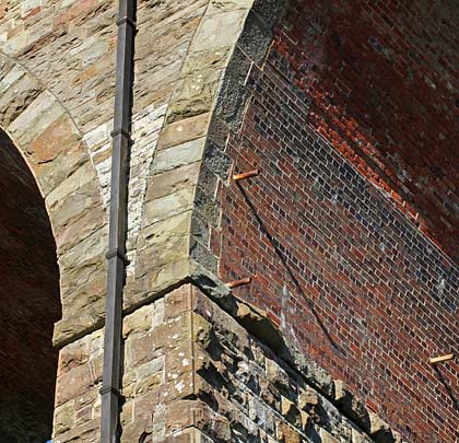 Stone piers and spandrels contrast with red brick arch soffits.