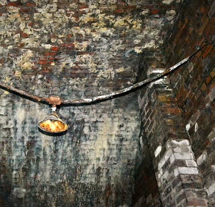 A rusting light fitting - slung between two blockwalls.
