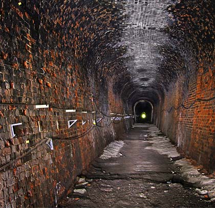 Lined in brick, the tunnel is horseshoe-shaped in profile, with a collection of fixtures and fittings on the sidewalls.