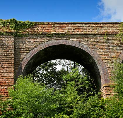 The main arches, which trees are conspiring to mask, are formed of five brick rings sitting on imposts above stone piers.