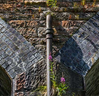 Downpipes bisect the skewback from which the arches spring.
