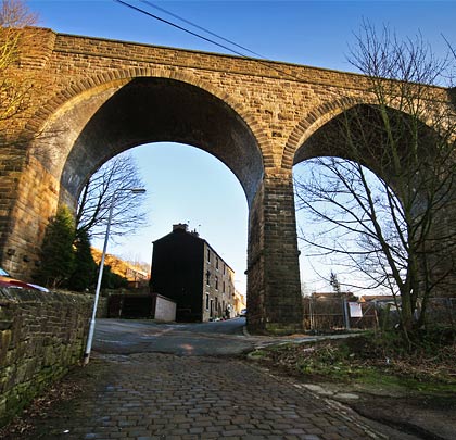 The viaduct overlooks a cobbled street as part of a scene that is acutely Northern.