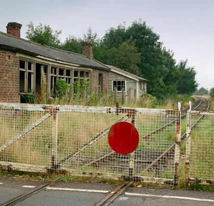 The main dilapidated building stands alongside a level crossing.