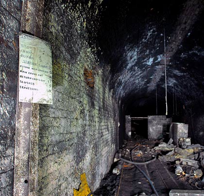 The tunnel is lined in blue engineering brick. This sign shows bell codes used during mine workings.