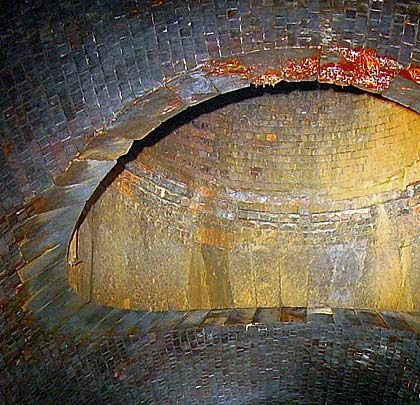 The shaft itself is brick-lined but the voussoirs at its base are stone.