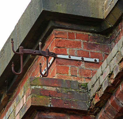 Topped with ashlar copings, the parapet still hosts a collection of brackets to which telegraph wires were attached.