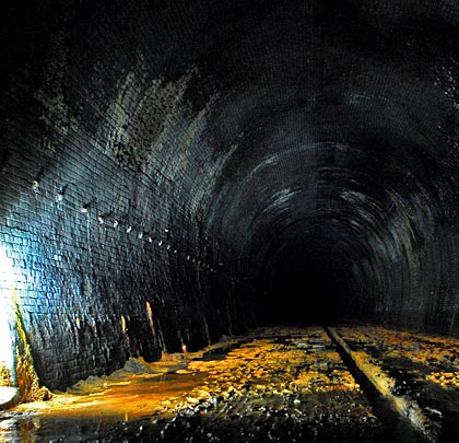 A row of cable hangers heads north into the gloom. Water and mud can reach a depth of 4 feet further into the tunnel.