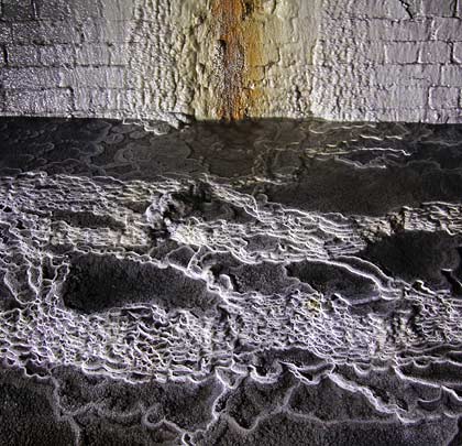 Large calcite deposits carpet the floor below one of the pipes.