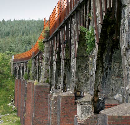 Vegetation, rust, cracks and crumbling brickwork combine to give the structure a particularly dilapidated appearance.