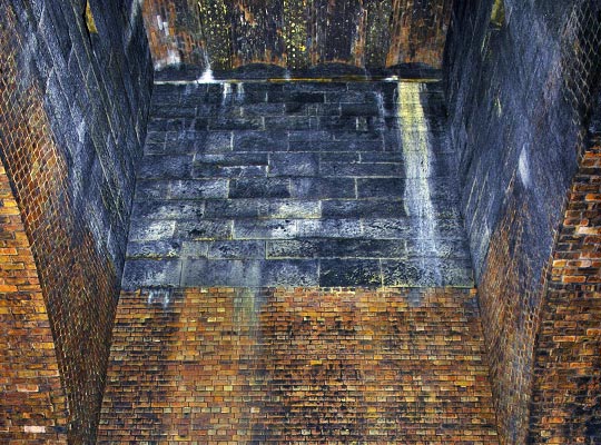 The upper part of the shaft is lined in neatly-masoned stone, above which is a vaulted brick roof.