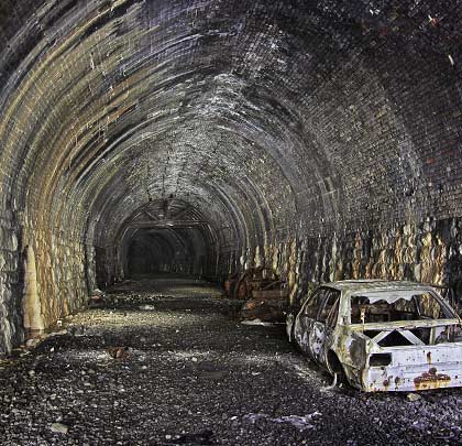 A collection of burnt-out cars are abandoned where penetrating water has added a calcite coating to the lining.