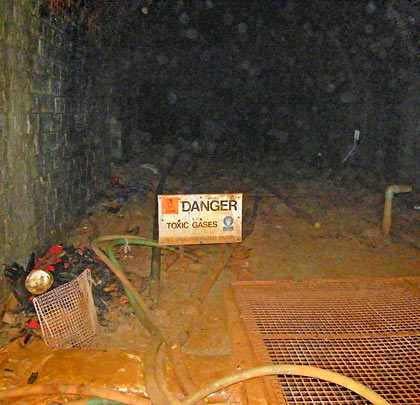 High levels of pungent gases create a serious hazard. The tunnel hosts assorted pipes and a rusting tank.
