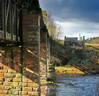 A derelict riverbank cottage hides in the viaduct's shadow.
