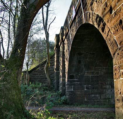 The westernmost arch span a road. The adjacent abutment boasts curved wing walls, as does its eastern counterpart.
