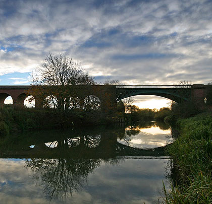 Sunset and viaduct reflect in the Derwent's tranquil waters.