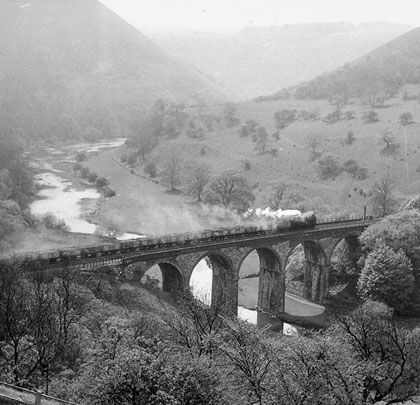 A steam-hauled freight heads west over the arches.