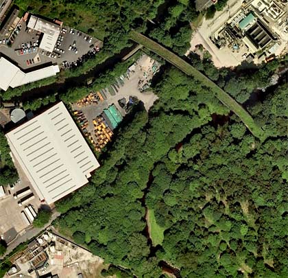 An aerial view shows how the structure fits itself between the adjacent factories and industrial units.