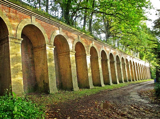 A length retaining wall - part of which is arched - supports Crystal Palace Parade above.